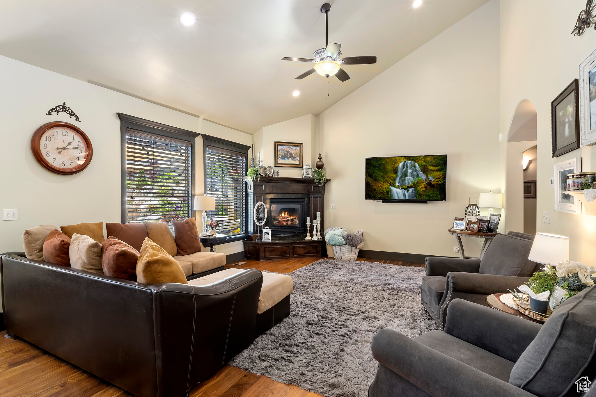 Living room featuring high vaulted ceiling, dark wood-type flooring, and ceiling fan