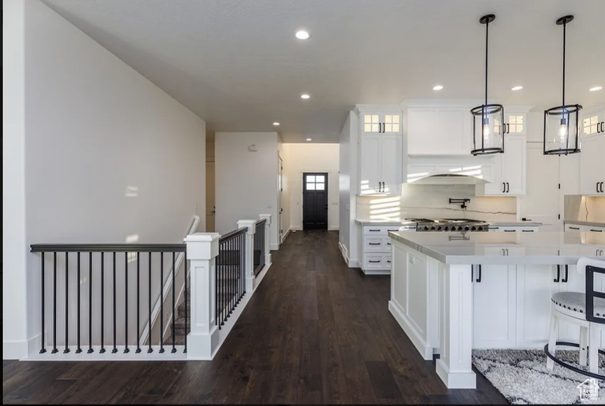 Kitchen with a kitchen island, white cabinetry, hanging light fixtures, backsplash, and dark hardwood / wood-style floors