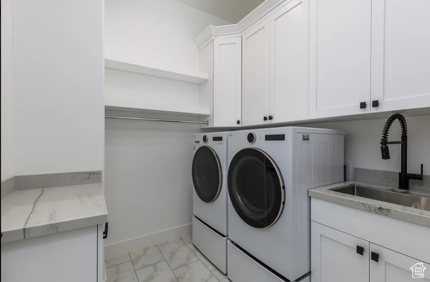 Laundry area featuring sink, light tile flooring, cabinets, and washing machine and dryer