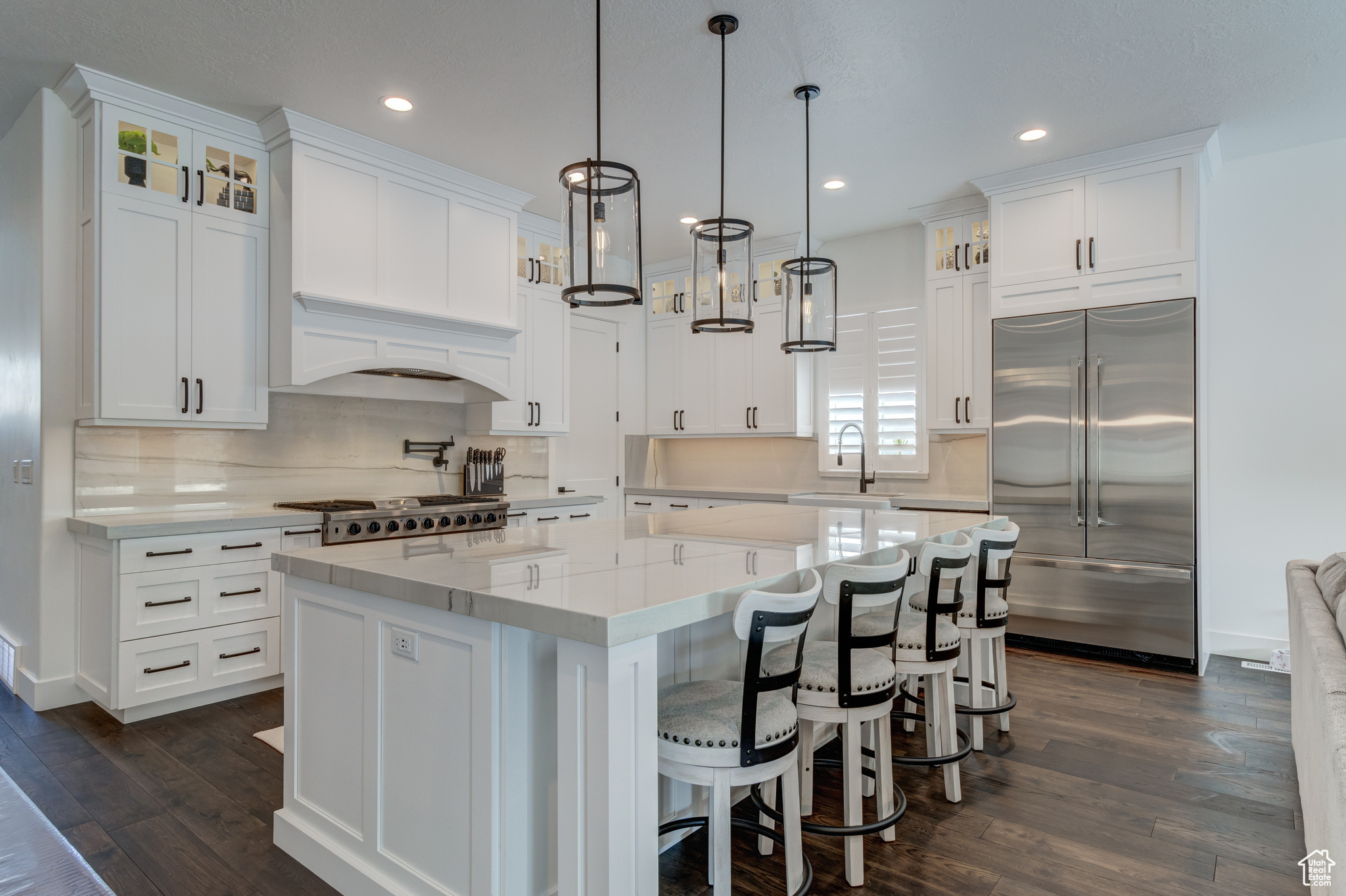 Kitchen with stainless steel built in fridge, decorative light fixtures, white cabinetry, and a center island