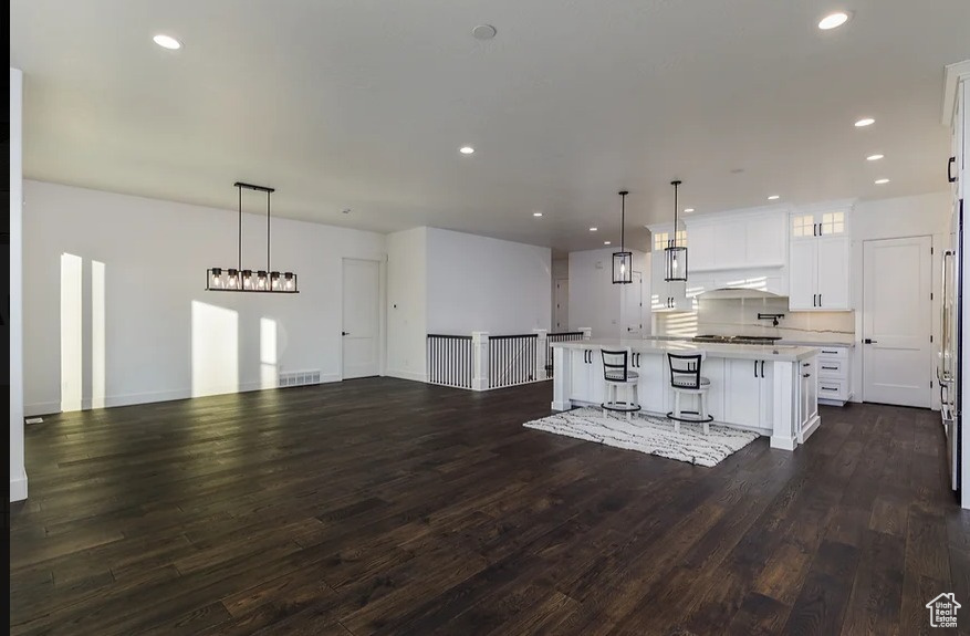 Kitchen featuring pendant lighting, dark hardwood / wood-style flooring, white cabinets, and a center island