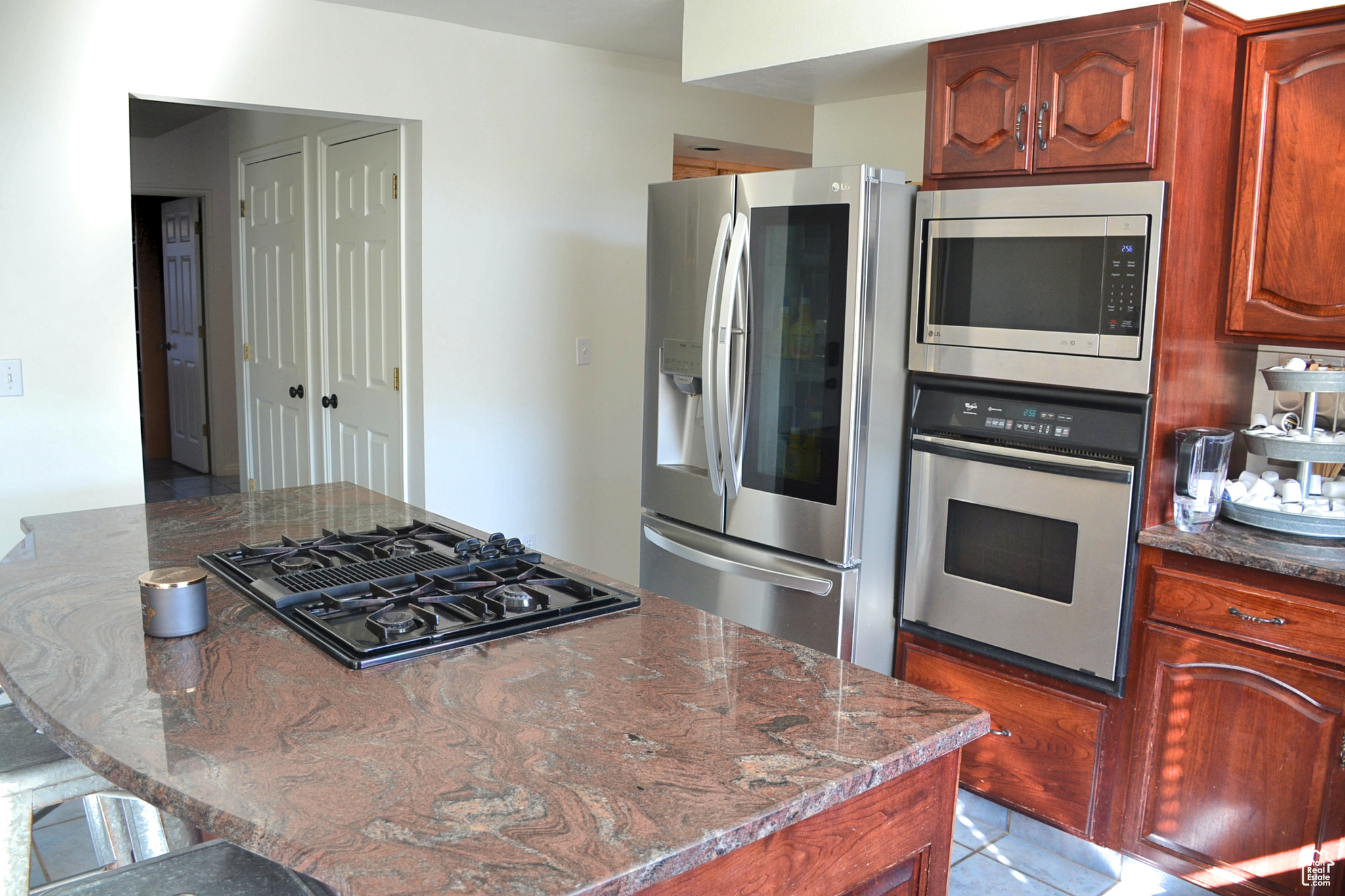 Kitchen with dark stone counters, a kitchen breakfast bar, appliances with stainless steel finishes, and light tile floors