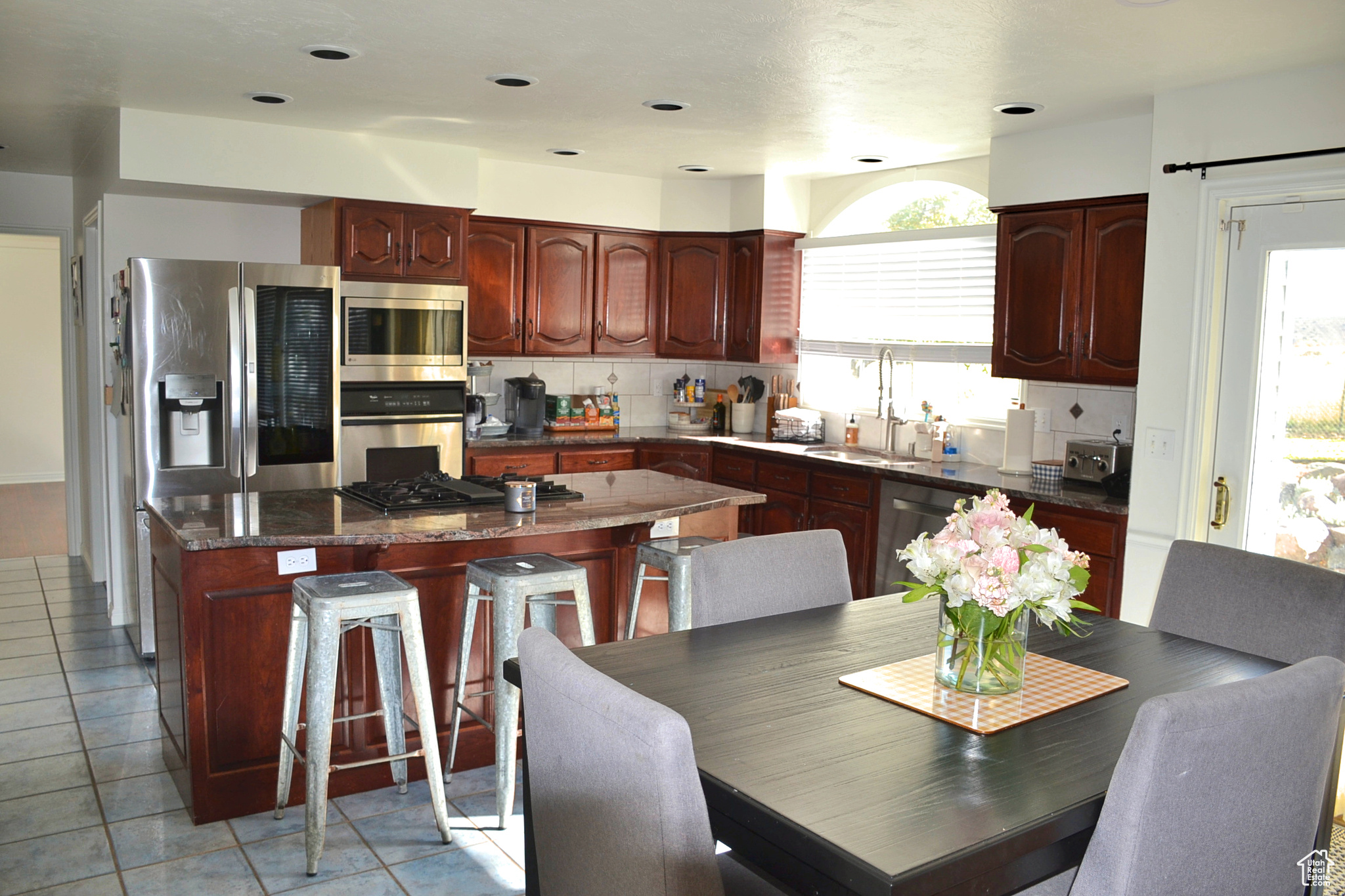 Kitchen with a kitchen island, light tile floors, tasteful backsplash, sink, and stainless steel appliances