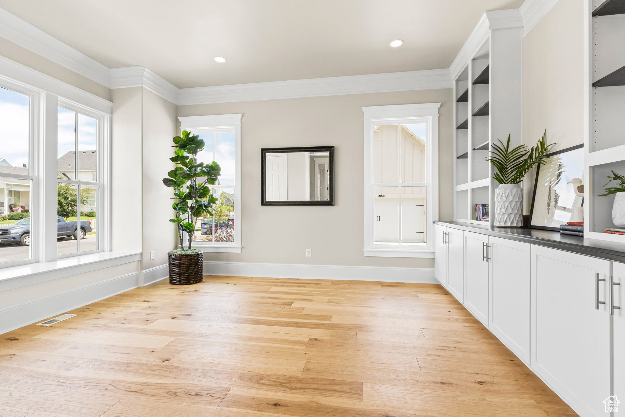 Interior space featuring crown molding, white cabinets, built in features, and light hardwood / wood-style floors