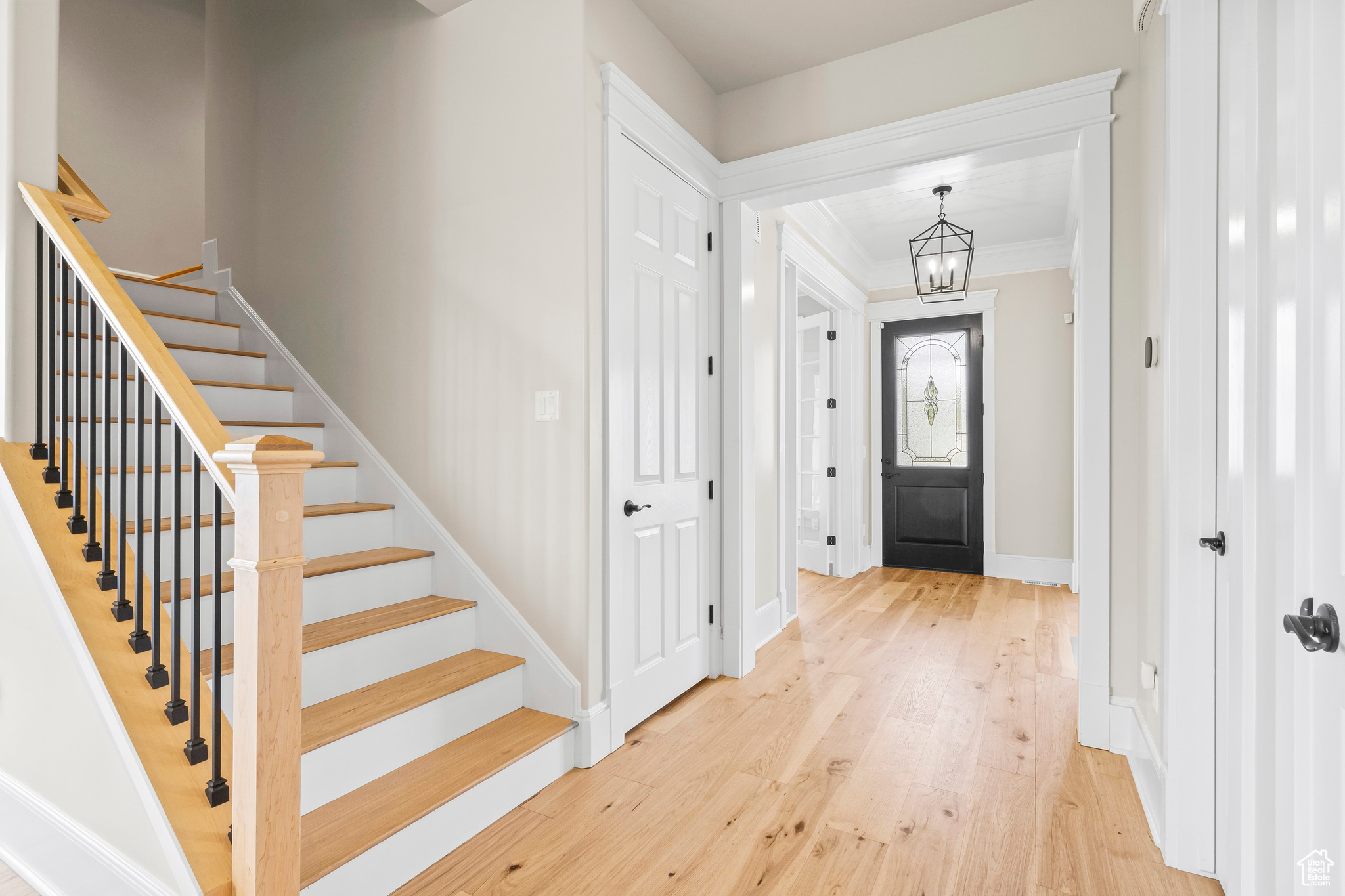 Foyer entrance with crown molding, a notable chandelier, and light hardwood / wood-style floors