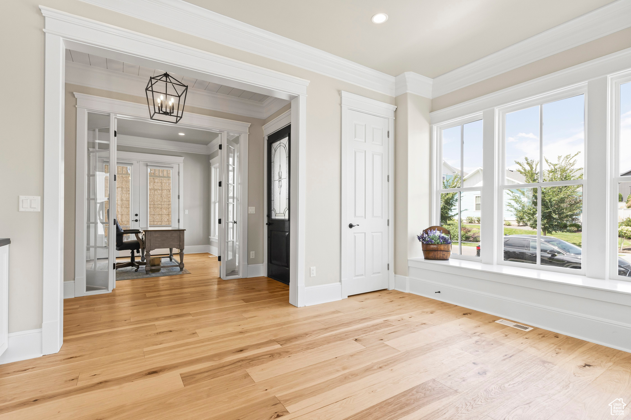 Entryway with ornamental molding and light hardwood / wood-style floors