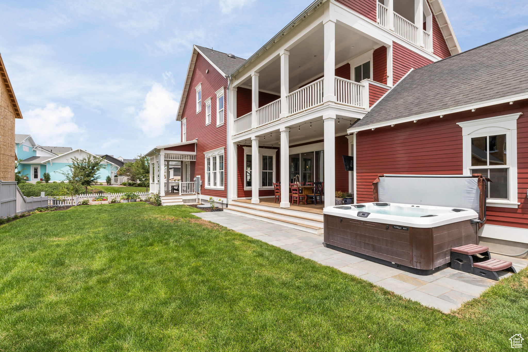 Rear view of house with a lawn, a hot tub, and a balcony