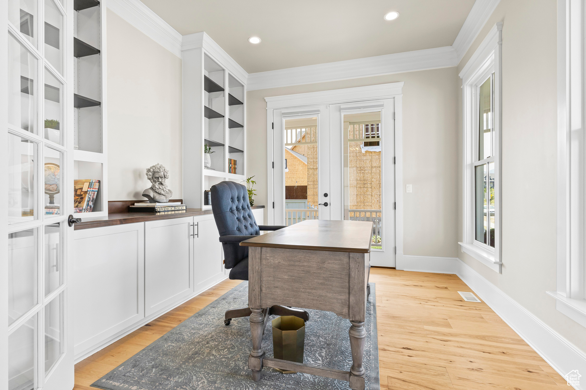 Office area featuring built in cabinets, light hardwood / wood-style flooring and crown molding