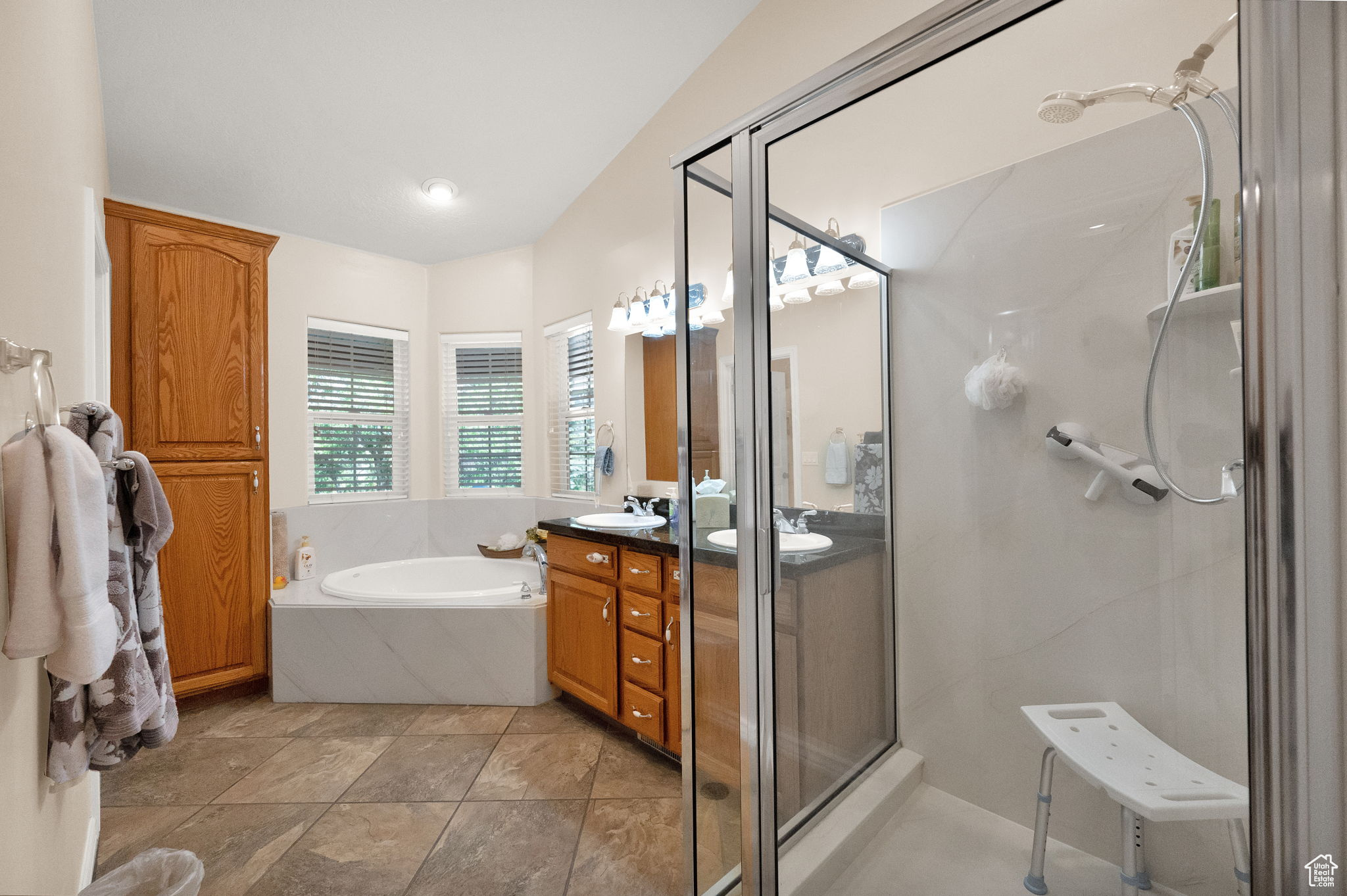 Bathroom featuring large vanity, double sink, separate shower and tub, and tile flooring