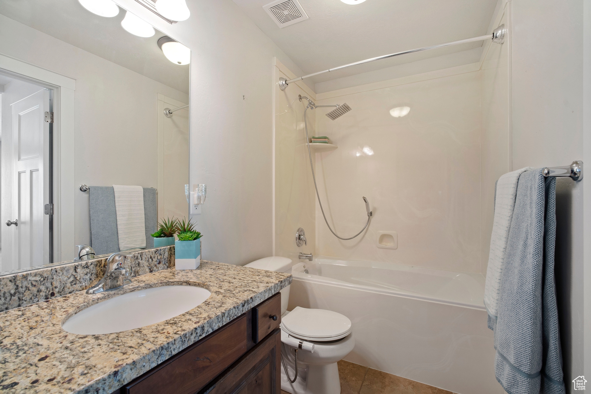 Full bathroom with tile floors, granite countertops, and upgraded shower fixture.