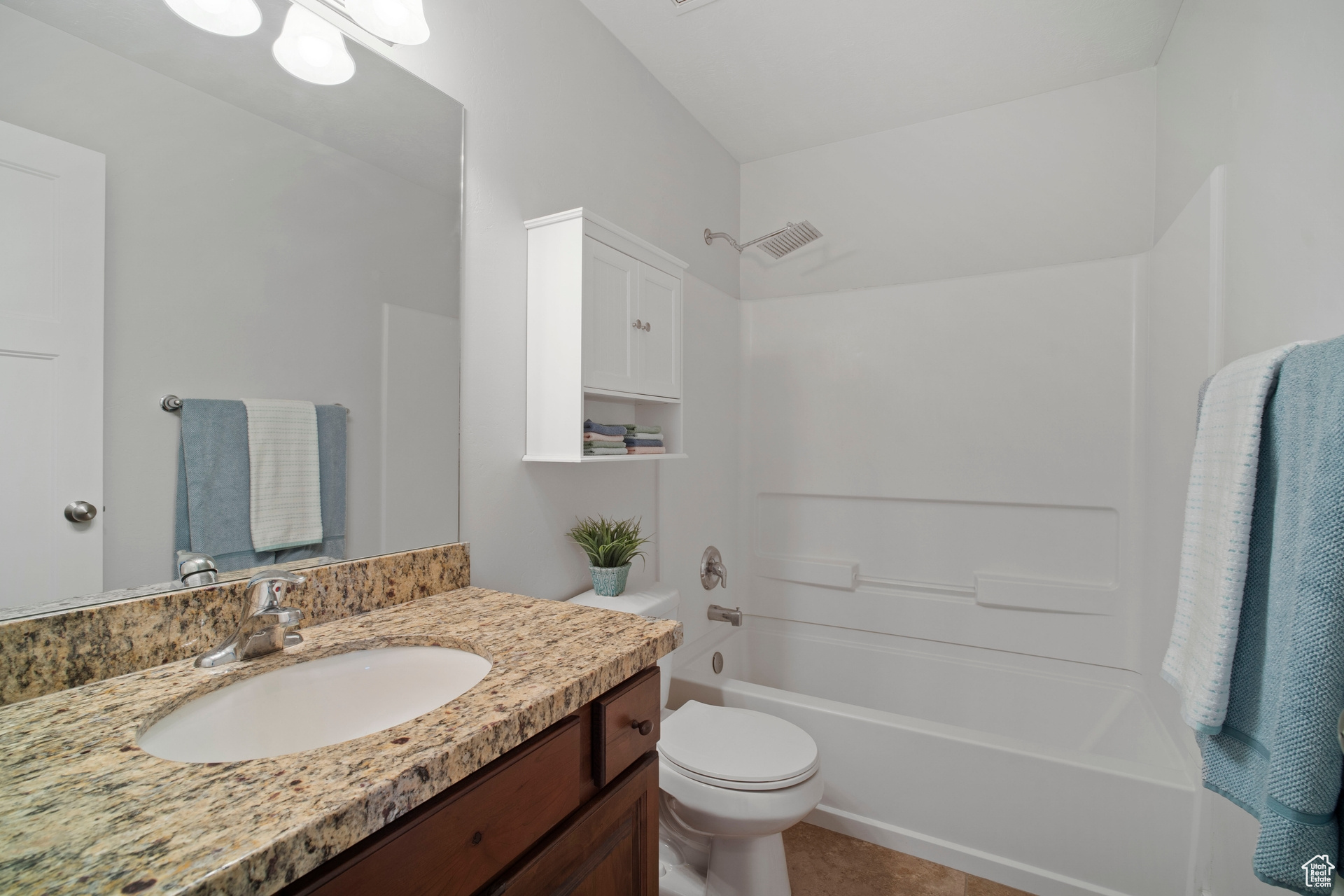 Full bathroom with tile floors, ample storage and upgraded shower fixture.