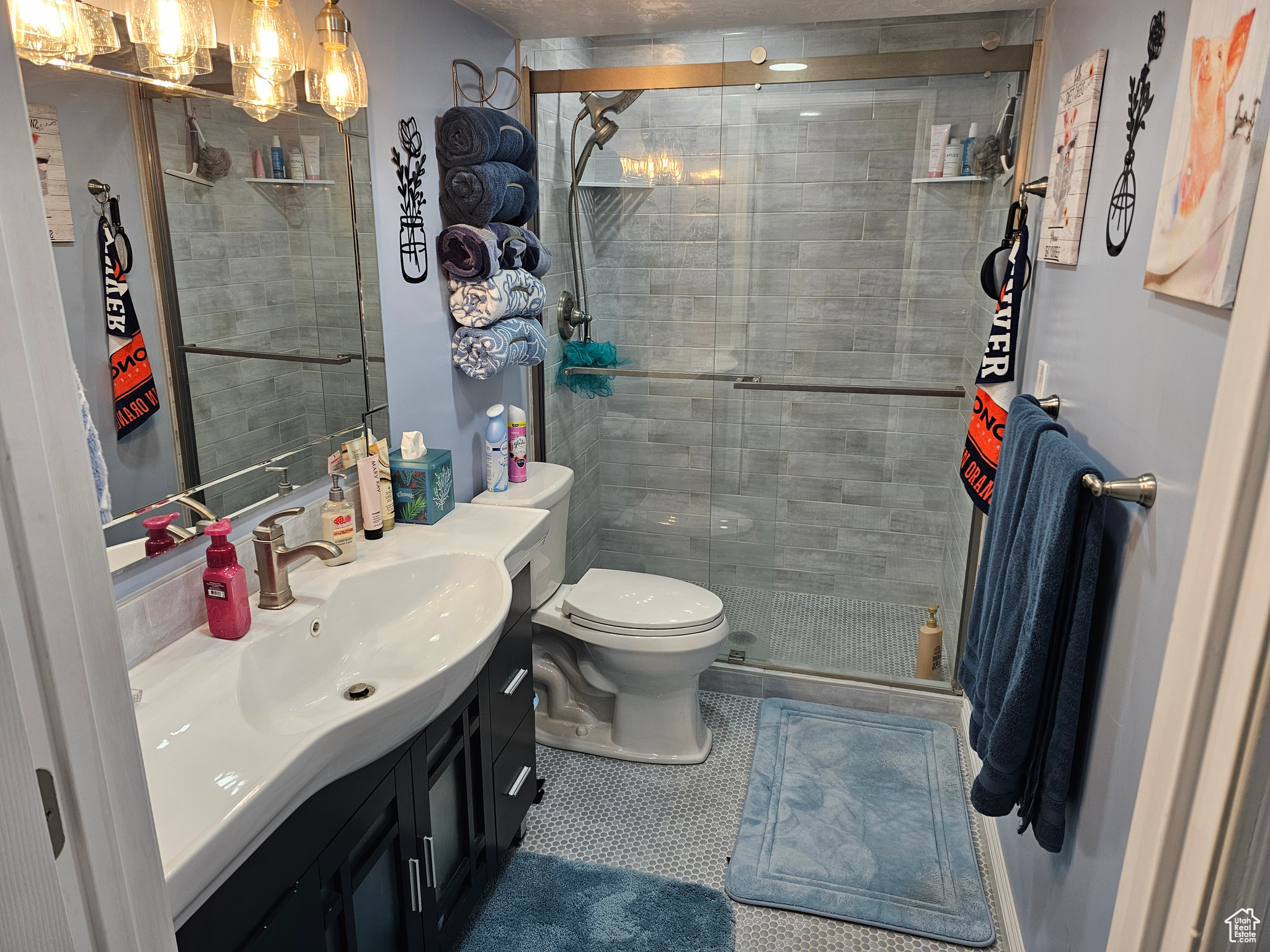 Bathroom featuring toilet, vanity, a shower with door, a chandelier, and tile flooring