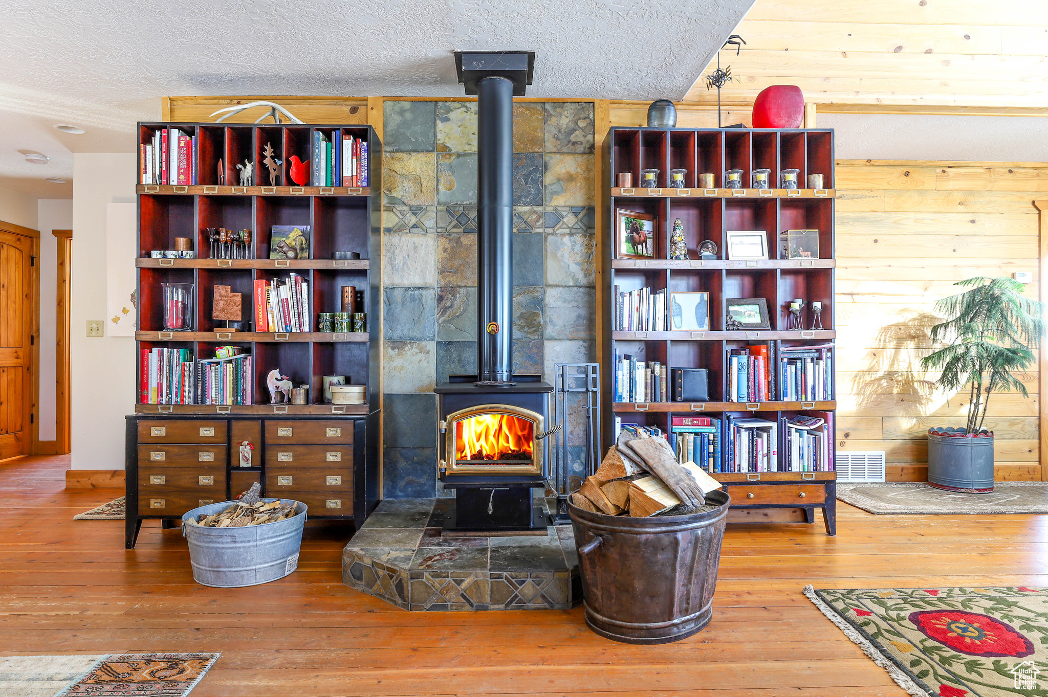Details featuring a wood stove, a textured ceiling, and hardwood / wood-style flooring