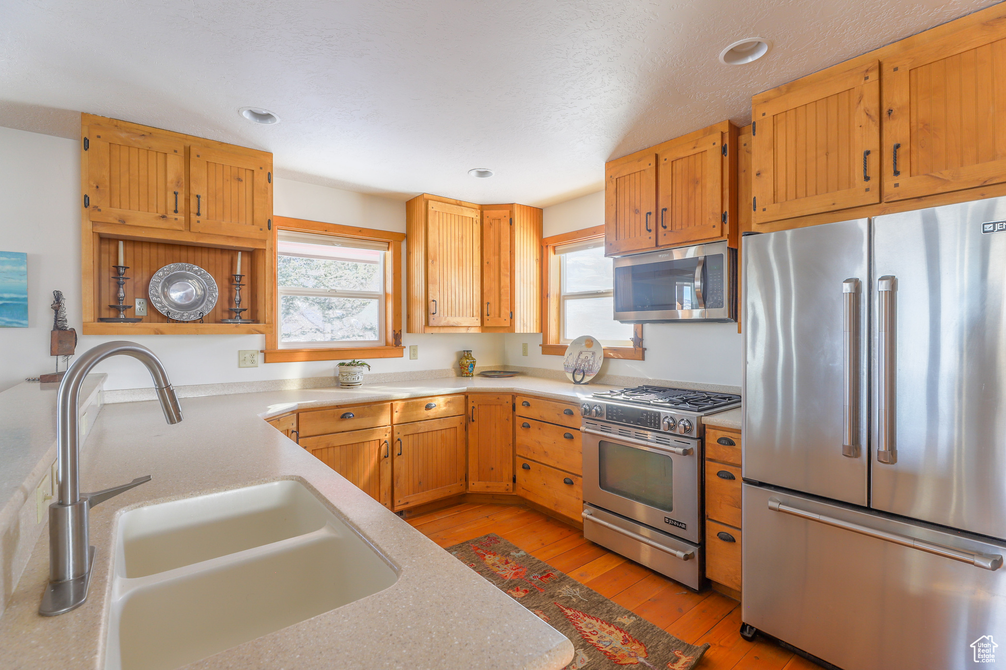 Kitchen with high end appliances, sink, light hardwood / wood-style floors, and plenty of natural light