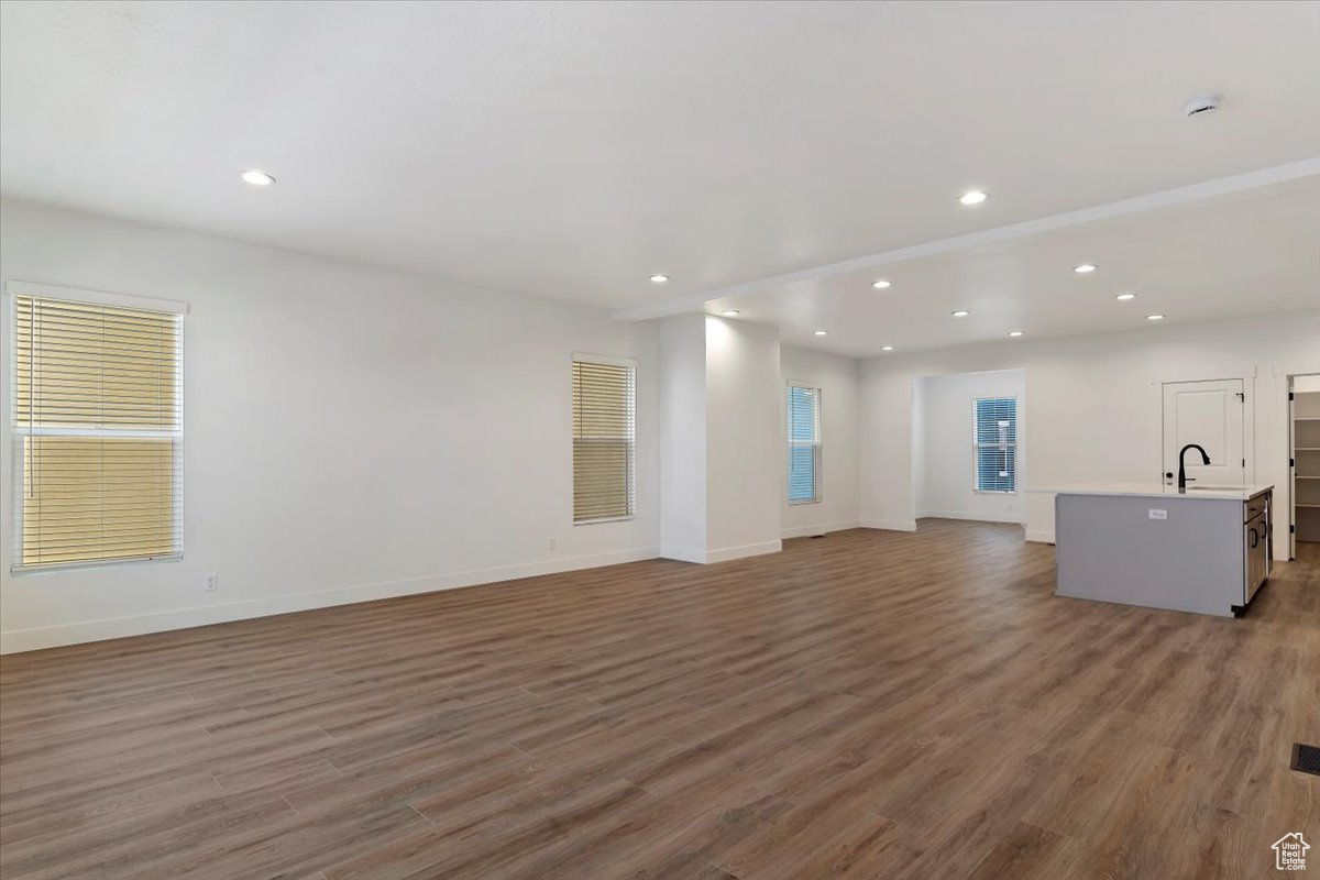 Unfurnished living room featuring dark hardwood / wood-style floors and sink