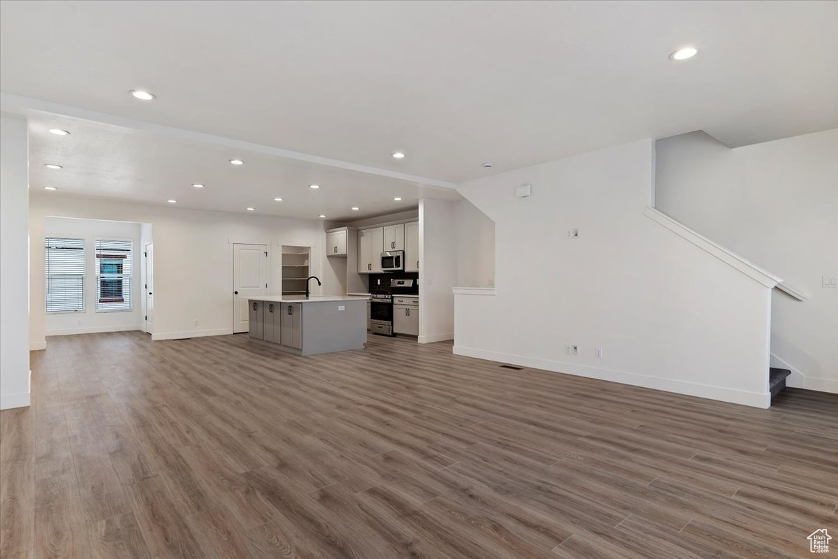 Unfurnished living room featuring sink and dark hardwood / wood-style floors