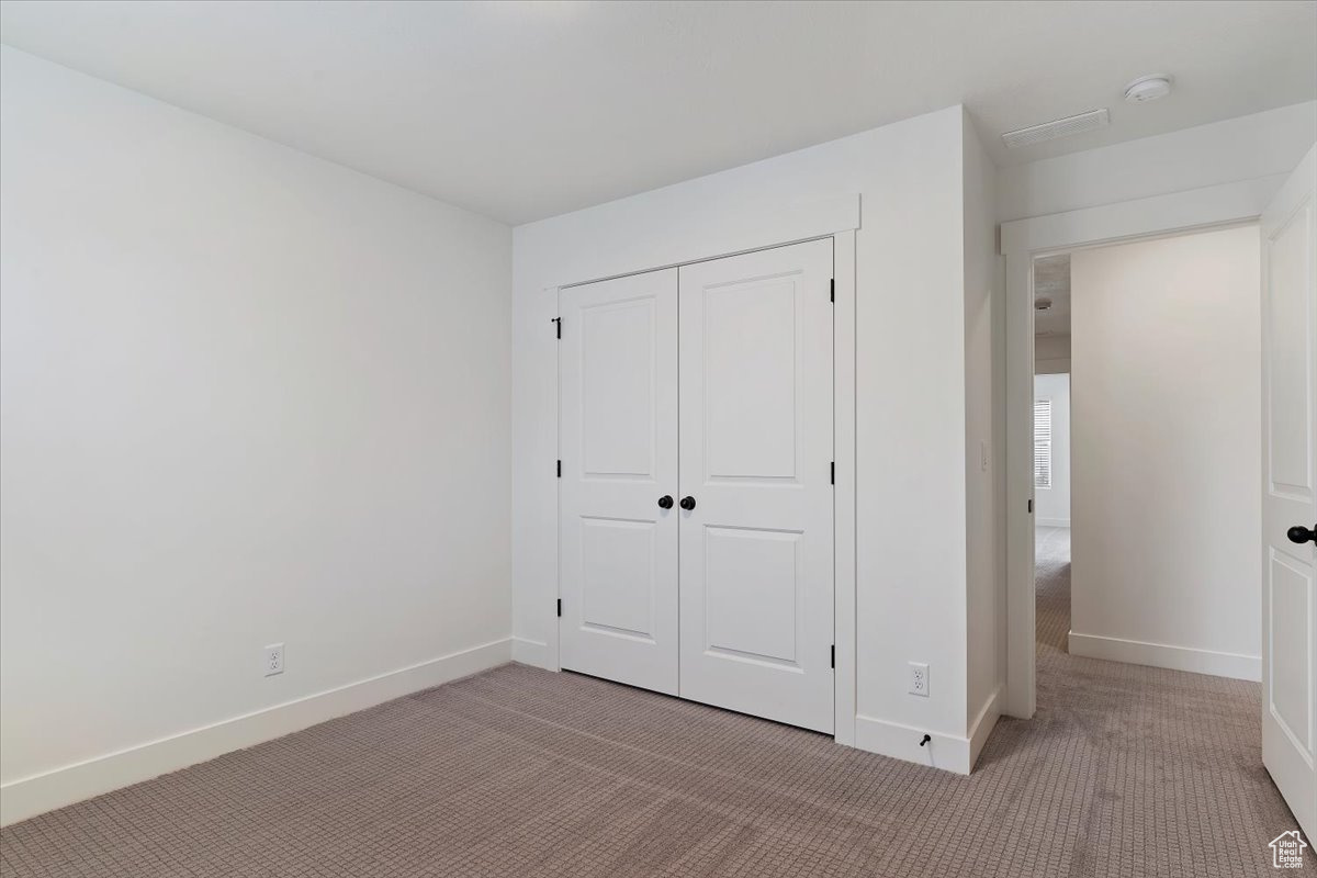 Unfurnished bedroom with light carpet and a closet