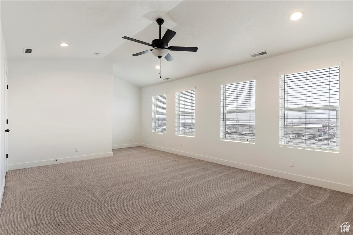 Unfurnished room featuring vaulted ceiling, light colored carpet, and ceiling fan