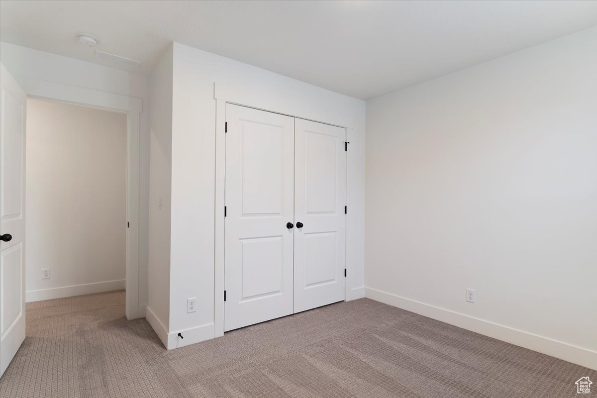 Unfurnished bedroom with light carpet and a closet