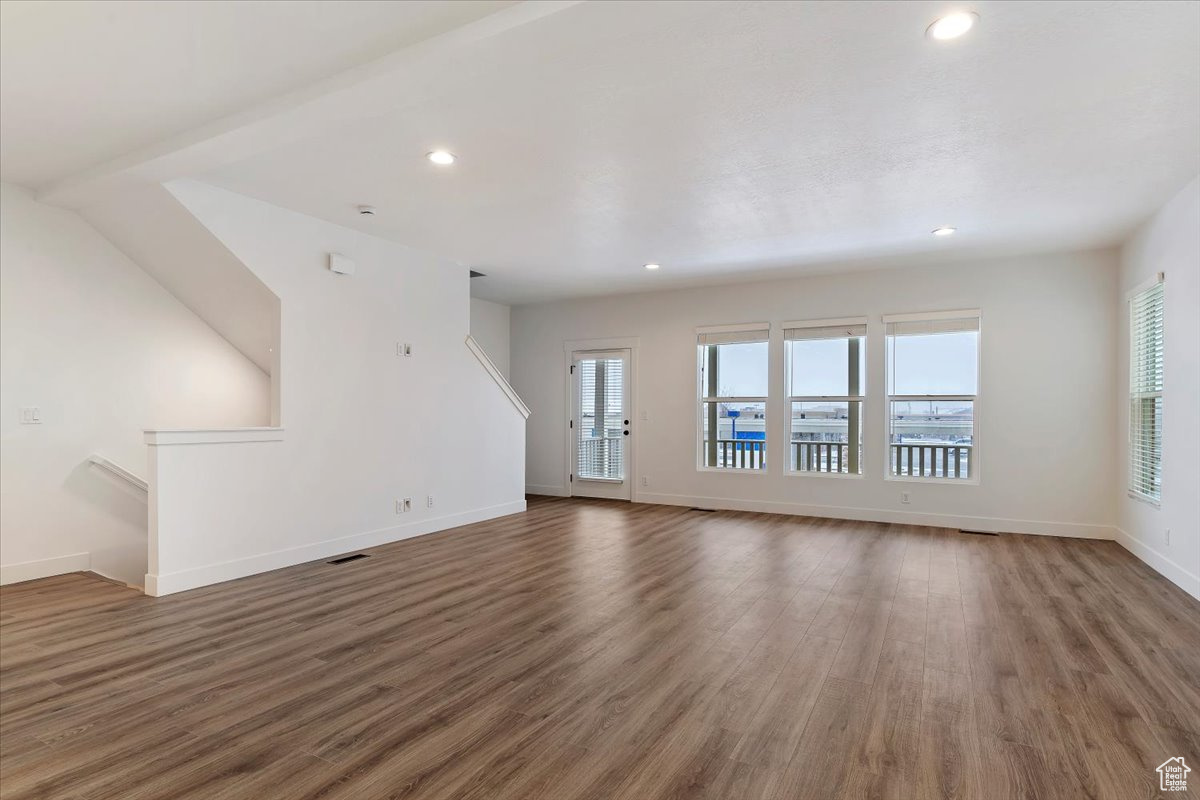 Unfurnished living room with dark wood-type flooring and a healthy amount of sunlight