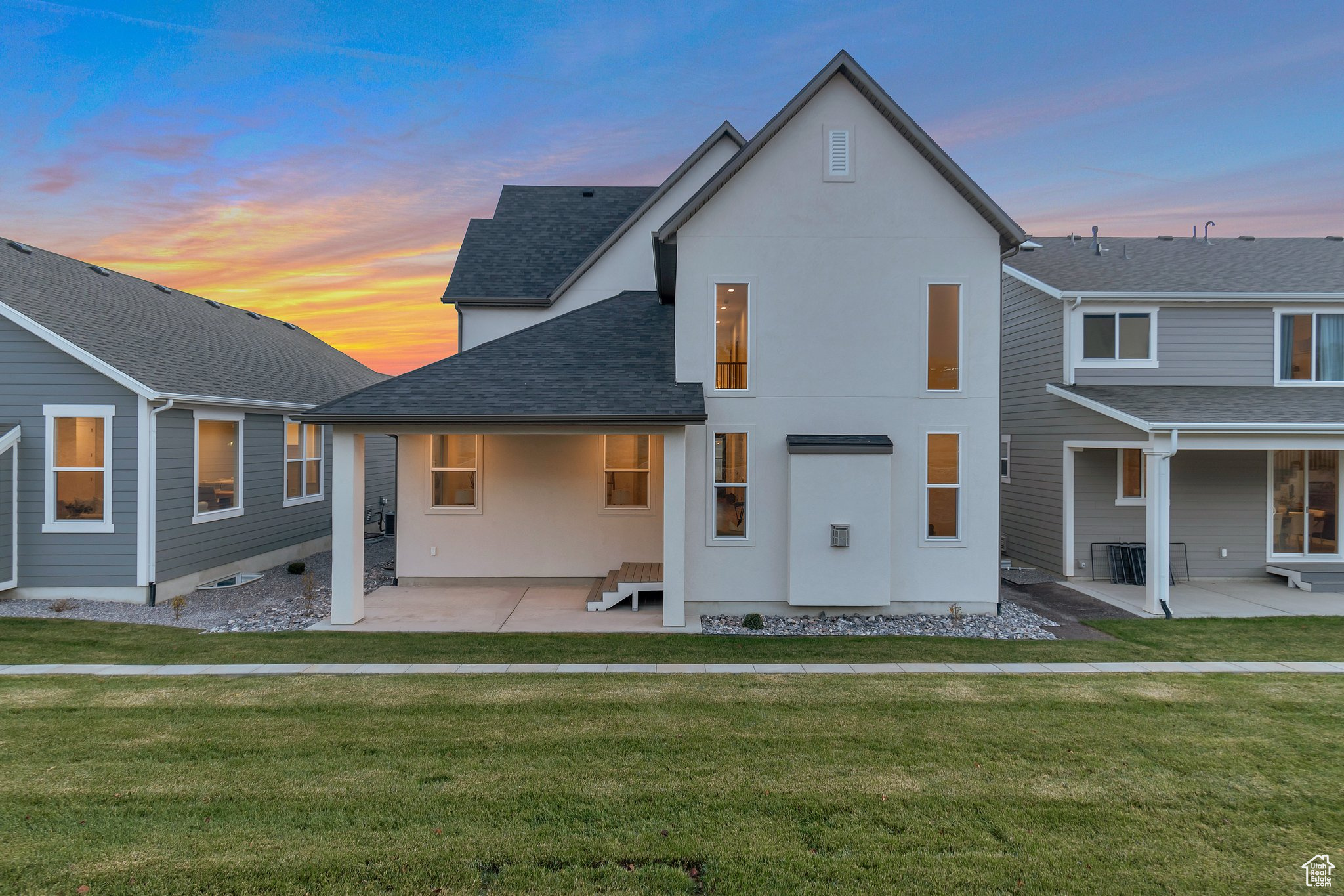 Back house at dusk with a lawn and a patio area