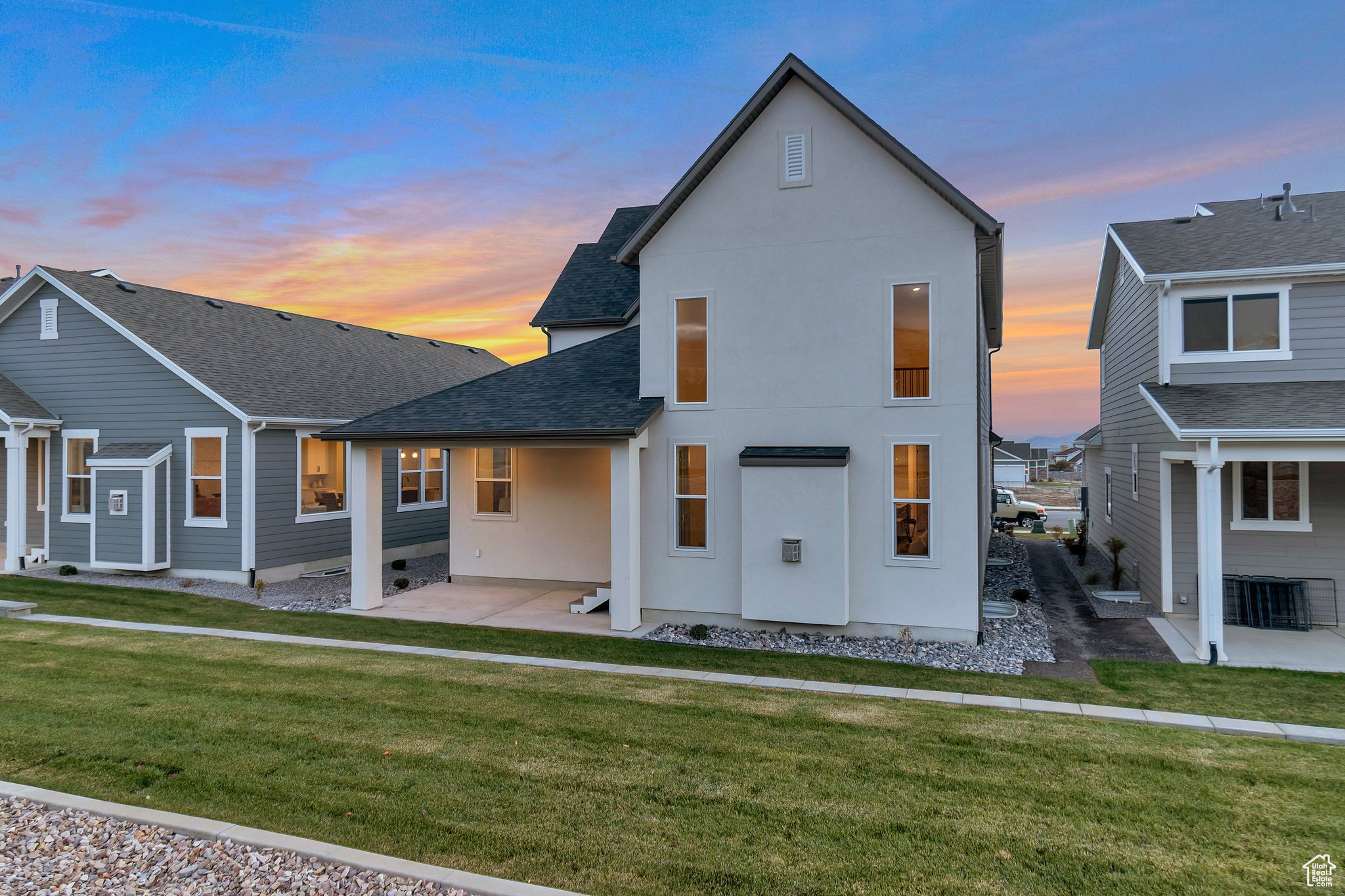 Back house at dusk featuring a yard and a patio area