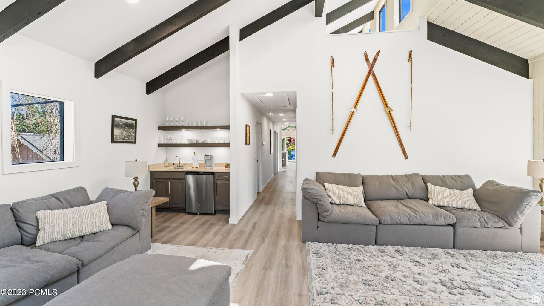 Living room with high vaulted ceiling, sink, light wood-type flooring, and beam ceiling