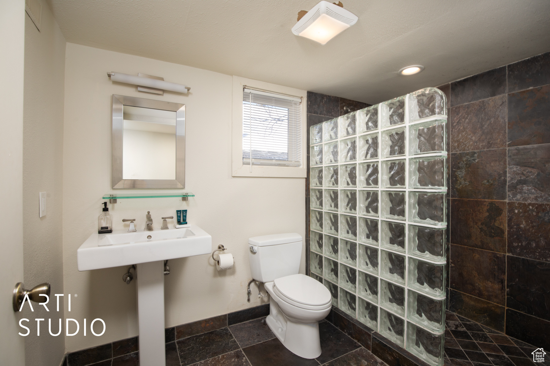 Bathroom featuring toilet, a tile shower, and tile flooring