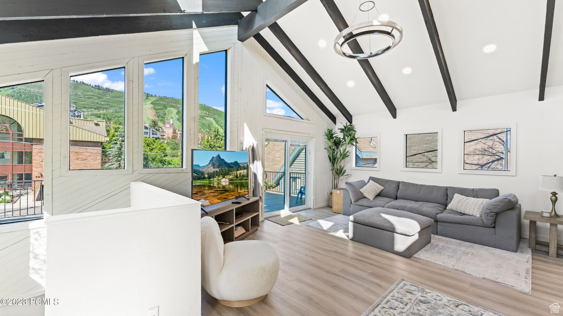 Living room with hardwood / wood-style floors, a notable chandelier, plenty of natural light, and beam ceiling