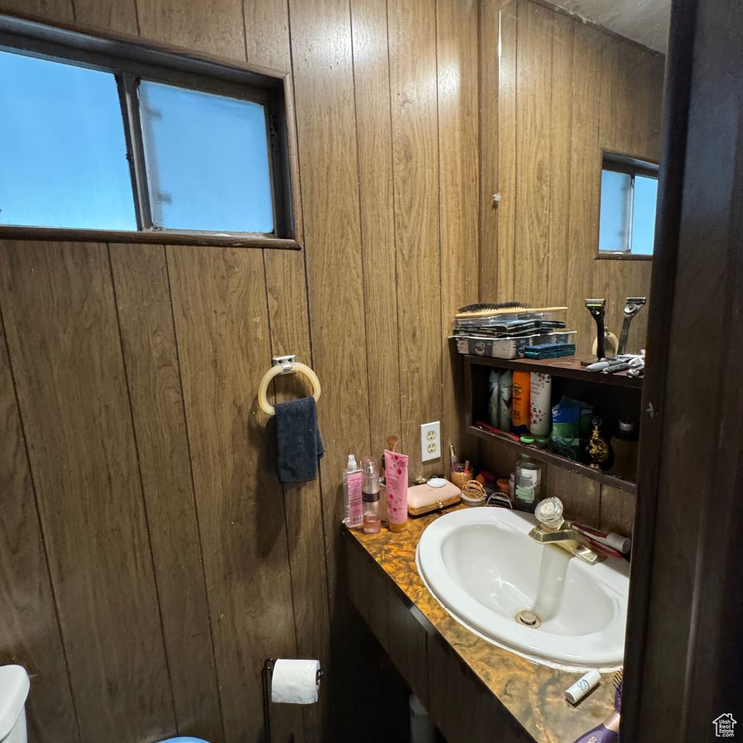 Bathroom with wooden walls, toilet, and vanity