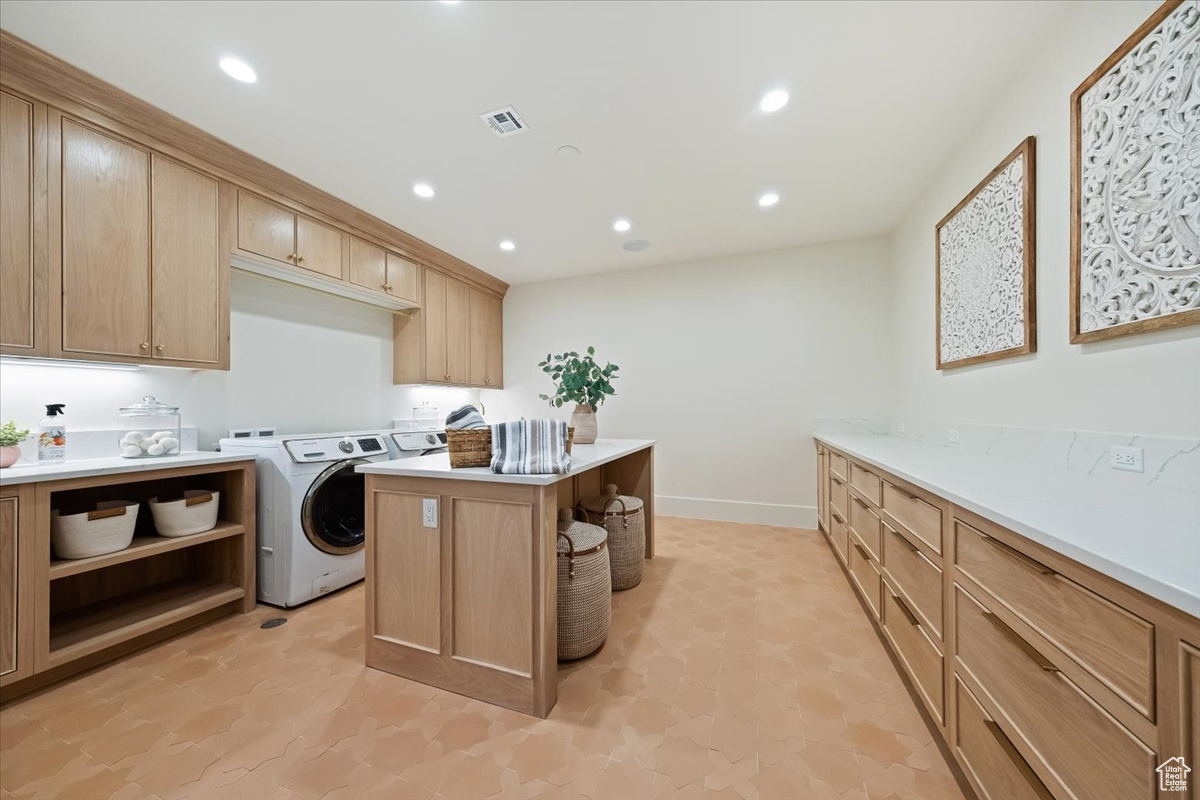 Laundry room with light tile flooring, cabinets, and washing machine and dryer