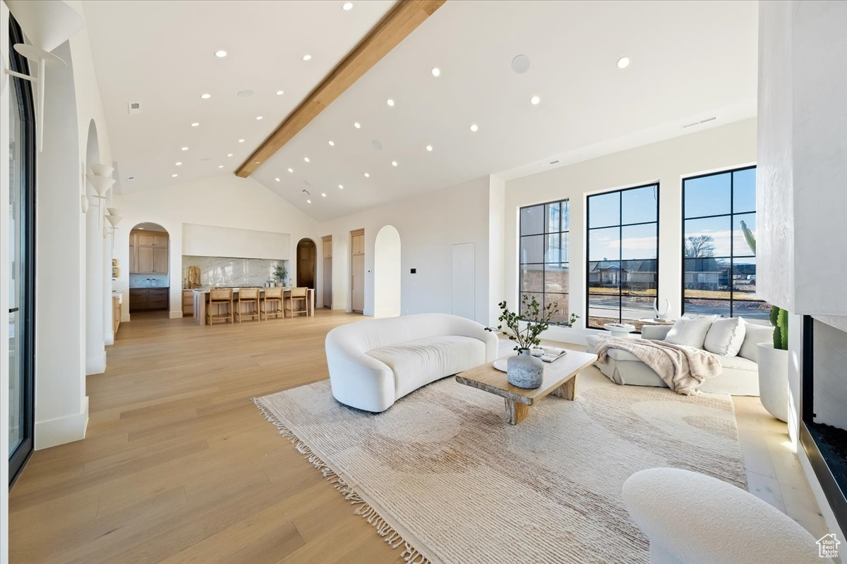 Living room featuring beam ceiling, light hardwood / wood-style floors, and high vaulted ceiling