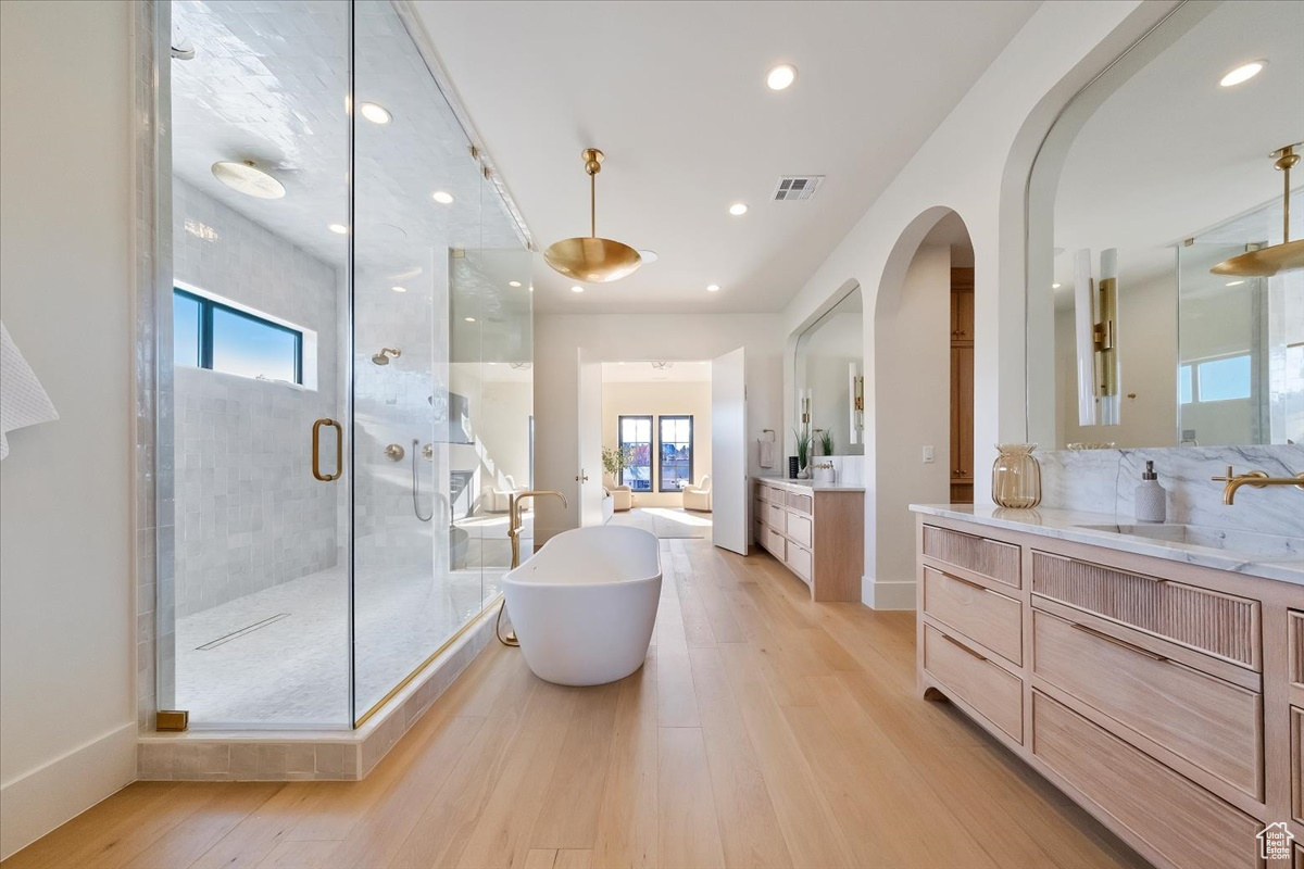 Bathroom featuring wood-type flooring, plus walk in shower, and oversized vanity