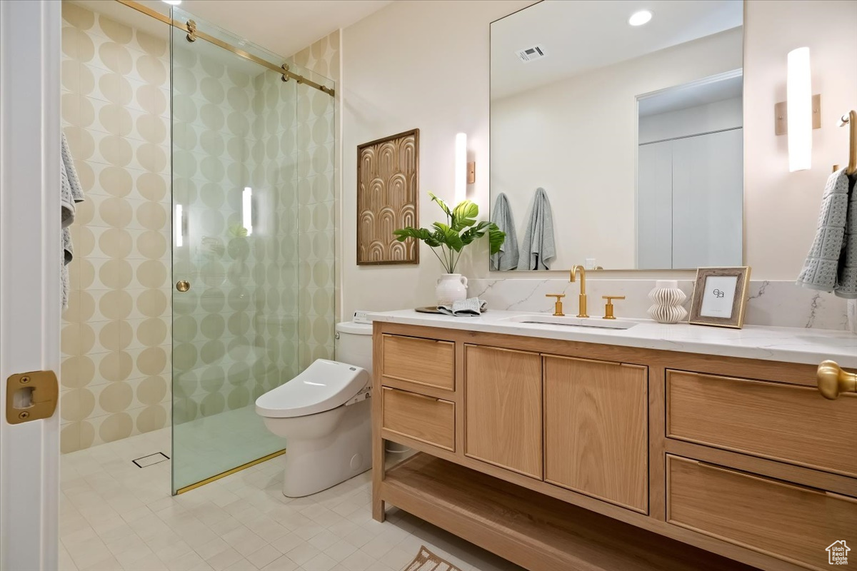 Bathroom featuring large vanity, tile floors, toilet, tasteful backsplash, and a shower with door