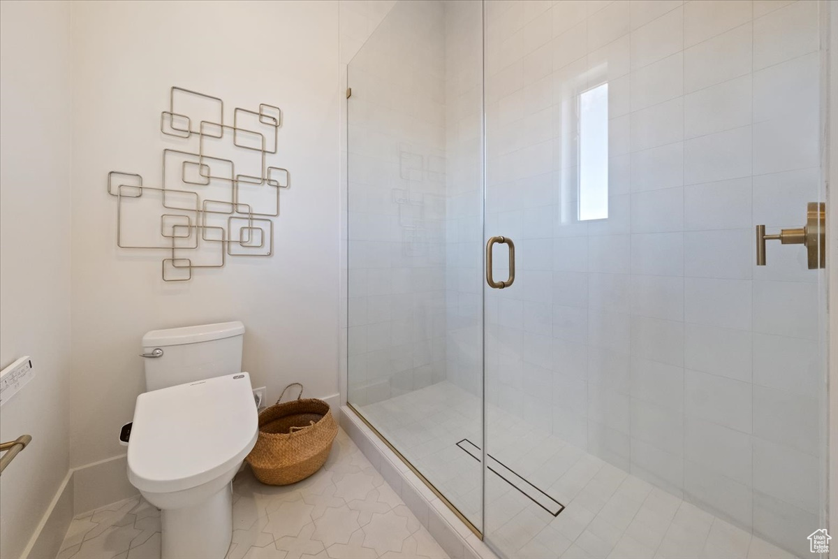 Bathroom featuring tile floors, toilet, and an enclosed shower