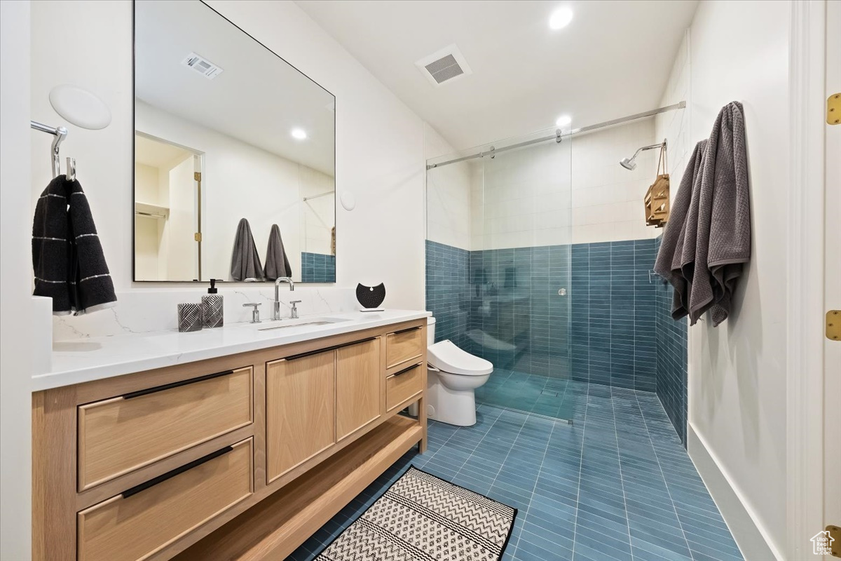 Bathroom with vanity, toilet, tile flooring, and a shower with door