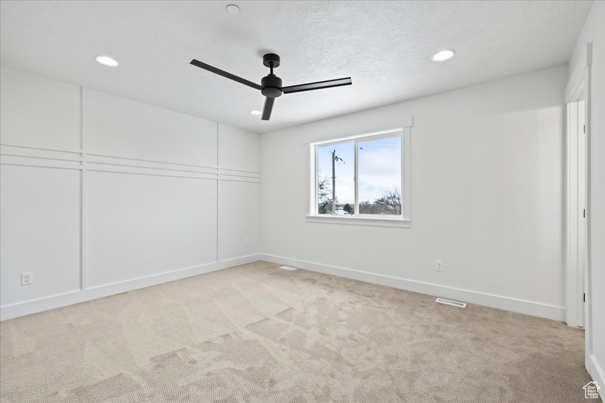 Carpeted spare room with ceiling fan