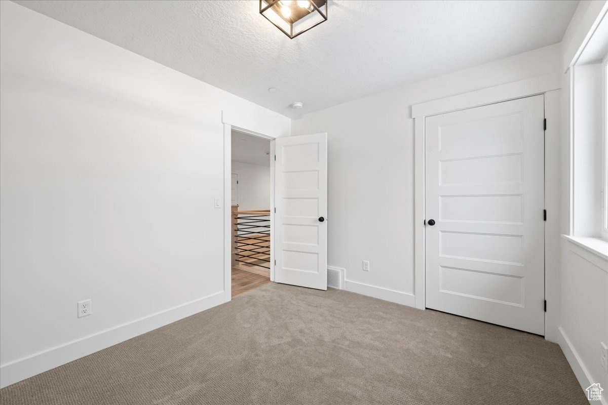 Unfurnished bedroom featuring a closet and light carpet