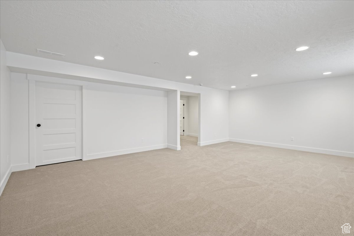 Basement with a textured ceiling and light carpet