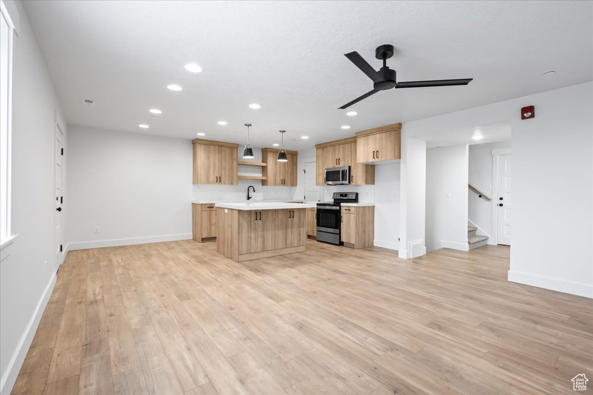 Kitchen with pendant lighting, light hardwood / wood-style flooring, a center island, stainless steel appliances, and ceiling fan