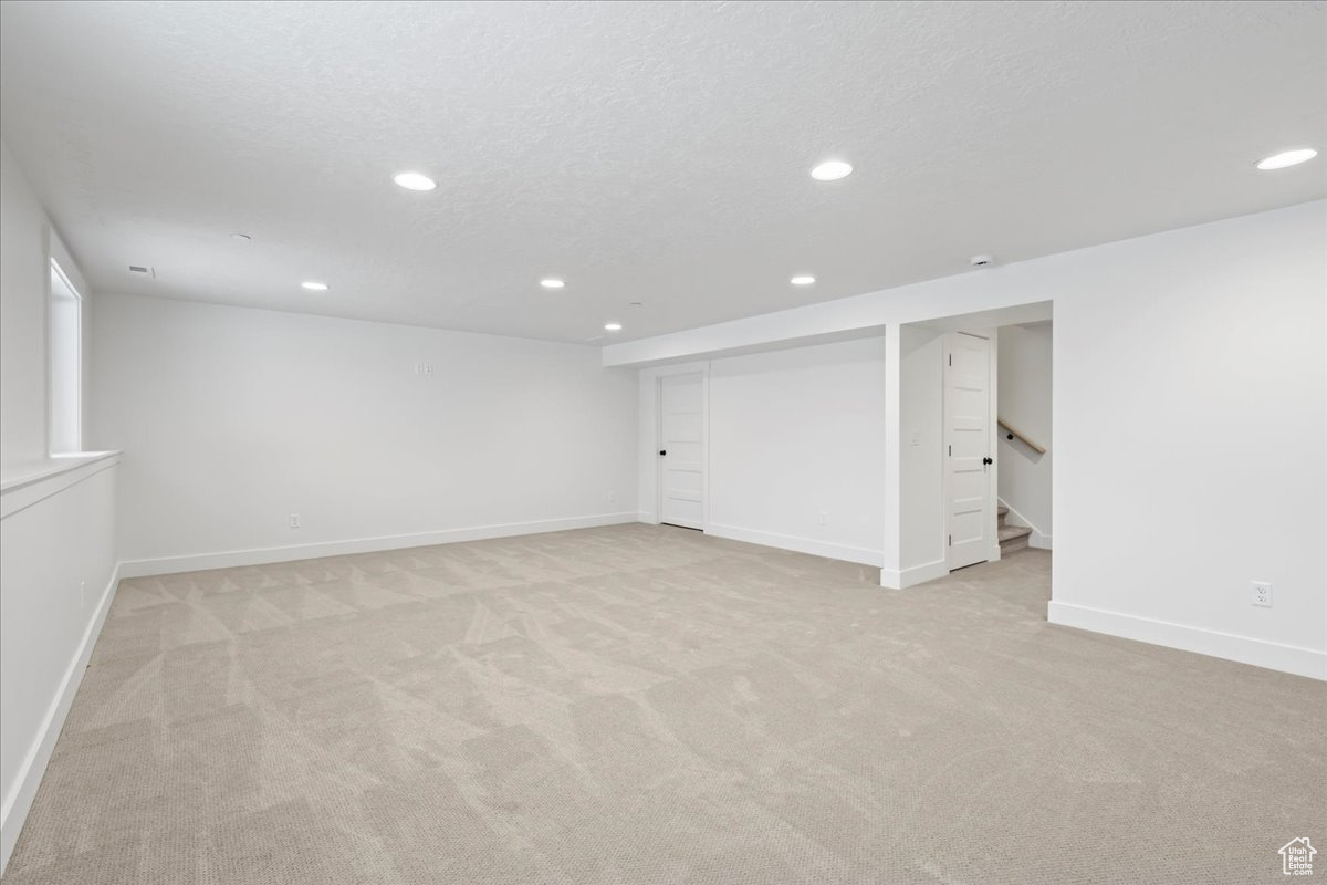 Basement with a textured ceiling and light carpet