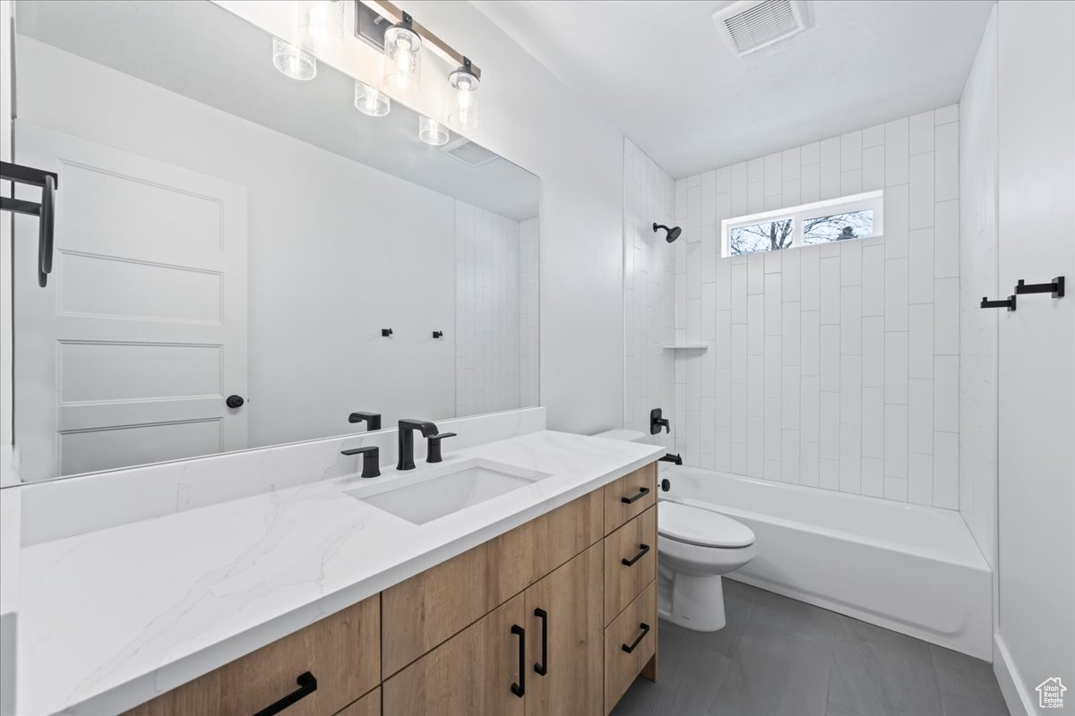 Full bathroom featuring tile floors, tiled shower / bath, toilet, and large vanity