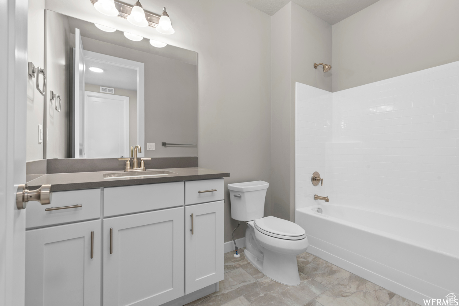 Full bathroom with vanity, toilet, tile flooring, and shower / washtub combination