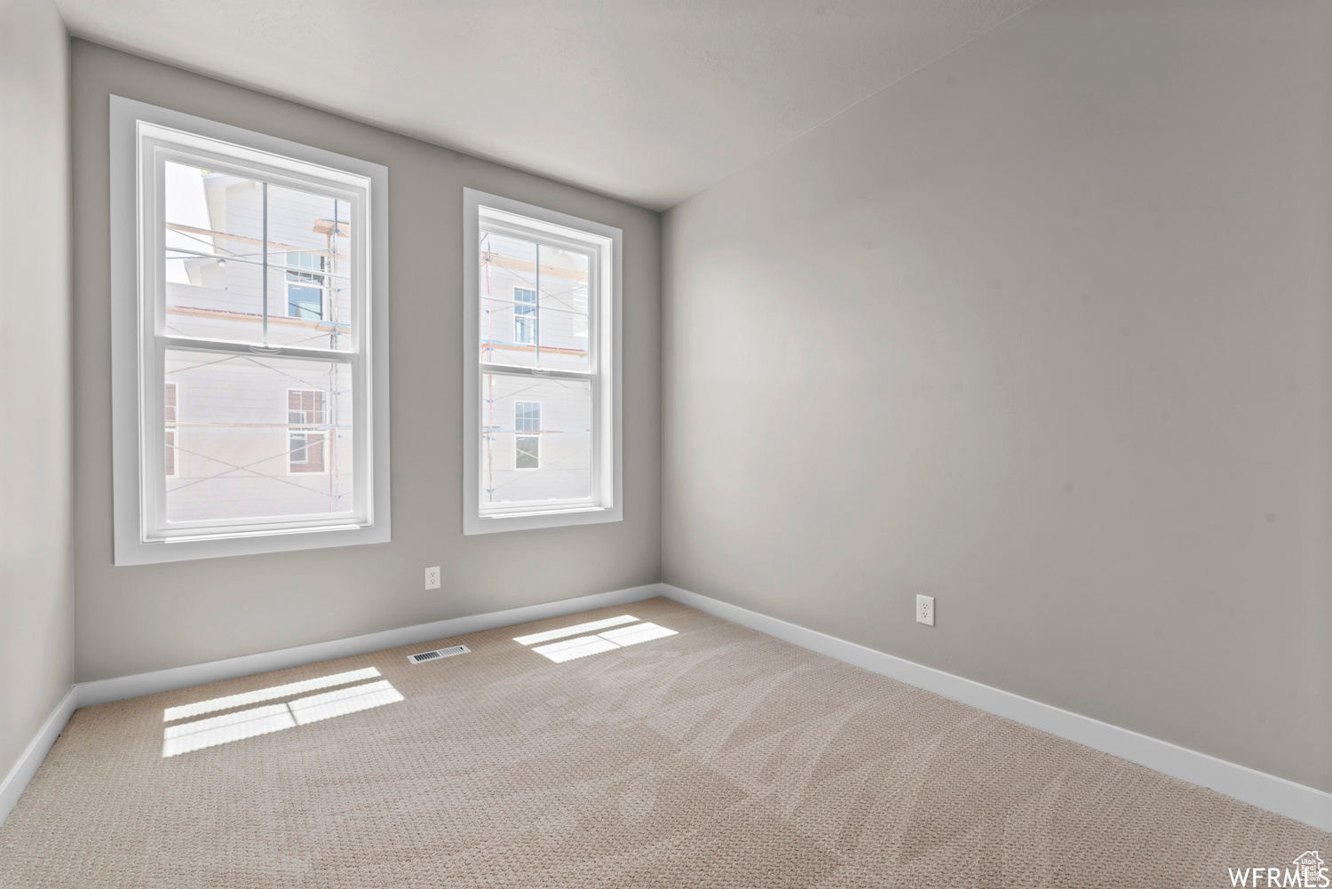 Empty room with a healthy amount of sunlight and light colored carpet