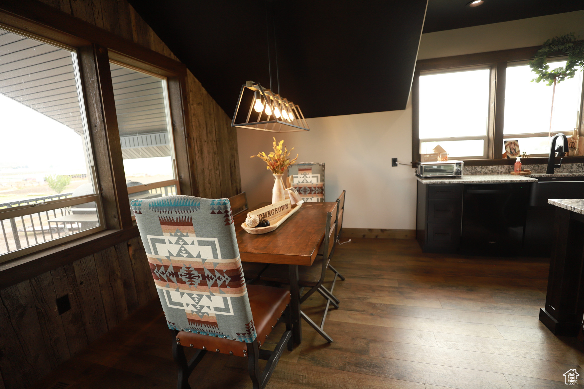 Dining room with dark hardwood / wood-style floors, wooden walls, vaulted ceiling, and plenty of natural light