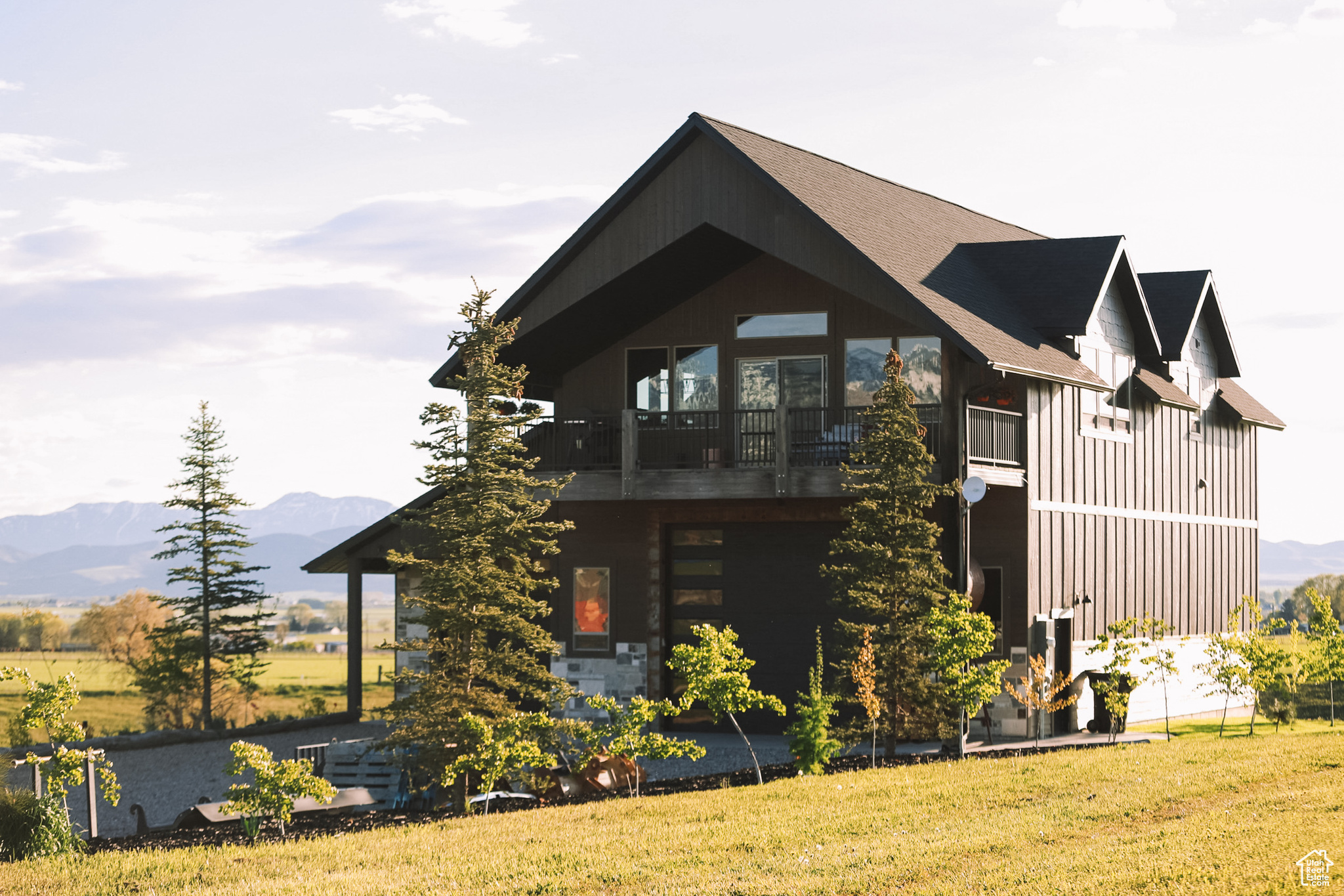 View of property exterior with a yard, a mountain view, mature trees, and a balcony.