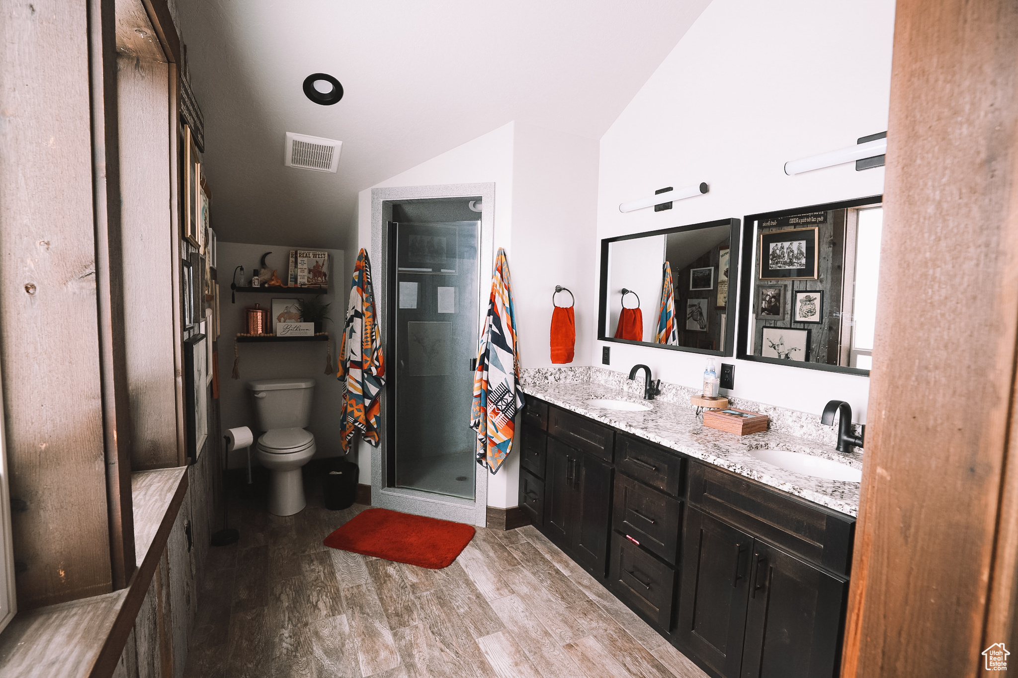 Bathroom featuring oversized vanity, wood-type flooring, double sink, toilet, and a shower