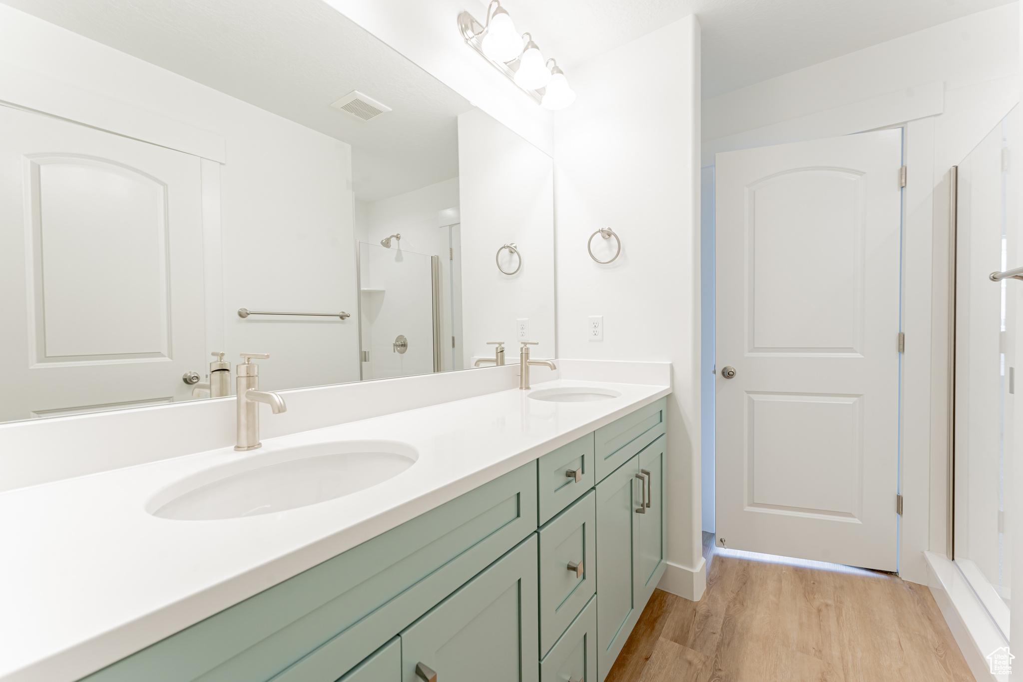 Bathroom with an enclosed shower, dual sinks, hardwood / wood-style flooring, and large vanity