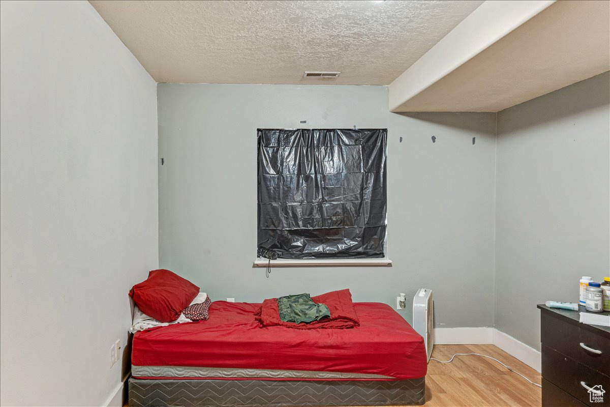 Bedroom featuring light hardwood / wood-style flooring and a textured ceiling