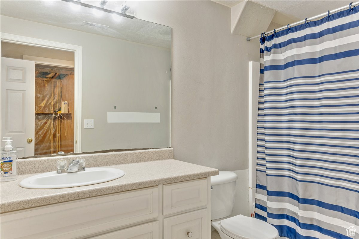 Bathroom featuring toilet and vanity with extensive cabinet space